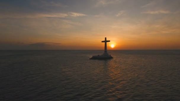 Katolska kors i havet vid solnedgången. — Stockvideo