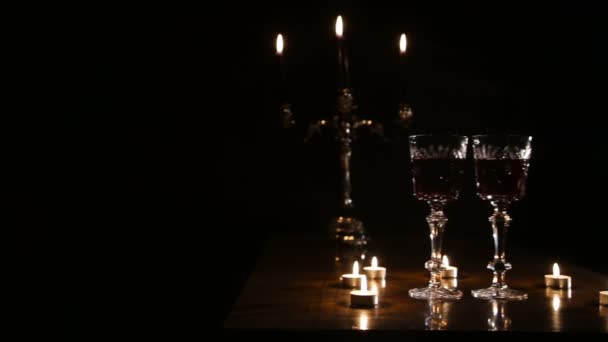 Weingläser und brennende Kerzen. — Stockvideo