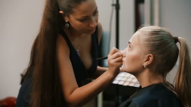 Make up artist gör professionell make up av ung kvinna — Stockvideo