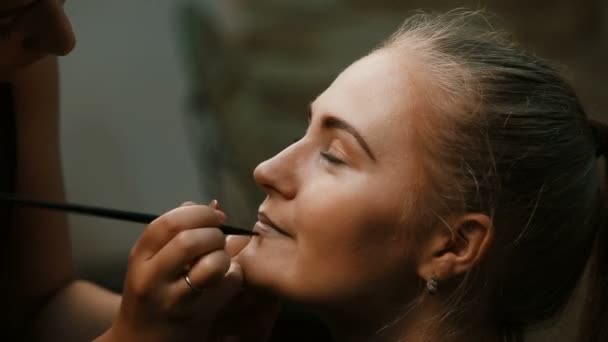 Makyöz, genç bir kadının profesyonel makyajını yapıyor. — Stok video