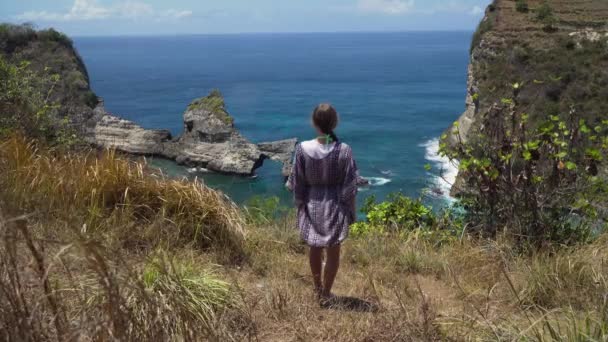 Dziewczyna stojąca na klifie i patrząca na morze. Bali, Indonezja — Wideo stockowe