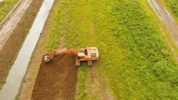 Grävskopa gräva ett dike i fältet. Antenn video. — Stockvideo
