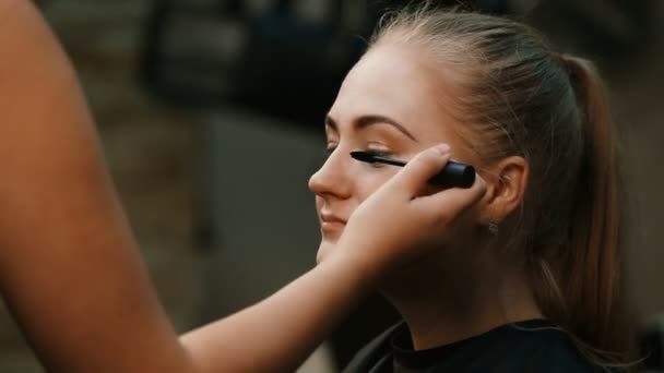 Maquillar artista haciendo profesional maquillaje de mujer joven — Vídeos de Stock