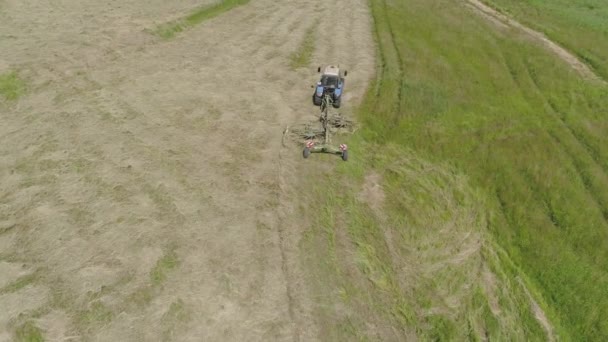 Ciągnik z przetrząsaczami grabi na polu uprawnym. — Wideo stockowe