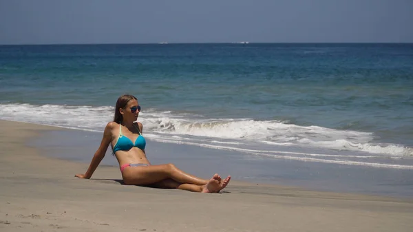 Ragazza sotto gli occhiali da sole si siede sulla spiaggia. — Foto Stock