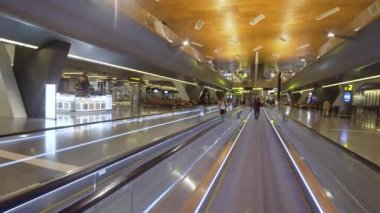 Bir sırt çantası havaalanında yatay bir yürüyen merdiven üzerinde olan kız. Modern bir Havalimanı turist. Dış yeni Hamad Uluslararası Havaalanı Doha, Katar. İçinde Havaalanı modern