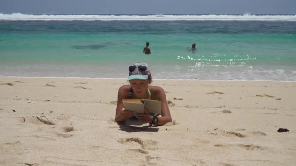 Menina na praia lendo um livro. — Vídeo de Stock