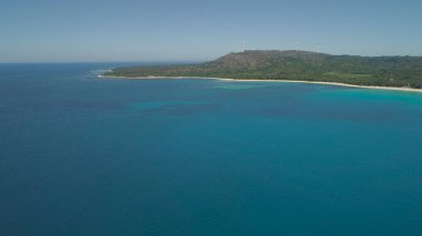 Kumsalı ve denizi olan deniz burnu, yel değirmenleri. Filipinler, Luzon.