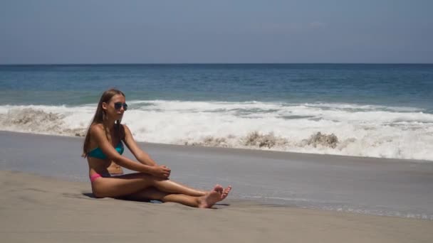 Fille dans les lunettes de soleil assis sur la plage. — Video