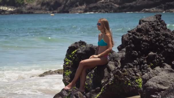 Ragazza si siede sulla roccia e guarda il mare. Bali, Indonesia — Video Stock