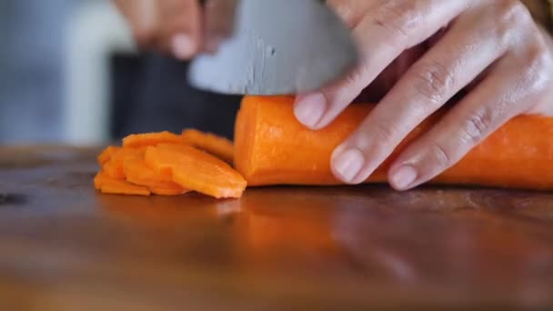 Hand med kniv skär morötter — Stockvideo