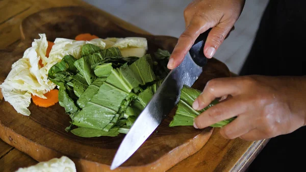 hand with knife cuts green onions