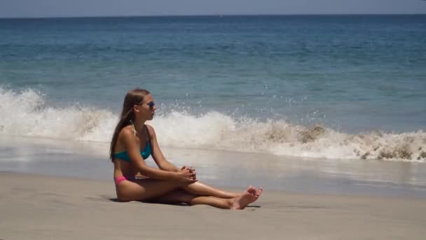 Meisje met de zonnebril zit op het strand. — Stockvideo