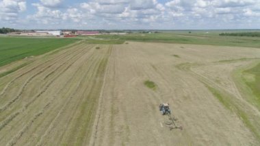 Tarlada tırmıkla tırmık taşıyan traktör..