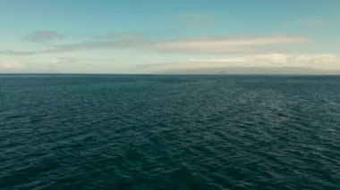 Deniz manzarası, mavi deniz, bulutlu ve adalı gökyüzü.