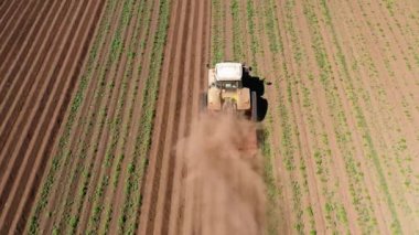 Patates tarlasında tarım makineleri toprağı işliyor.