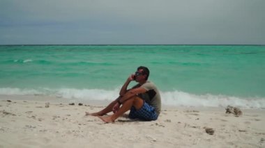 Sahilde cep telefonu olan bir adam..