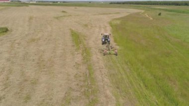 Tarlada tırmıkla tırmık taşıyan traktör..