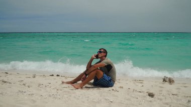 Sahilde cep telefonu olan bir adam..