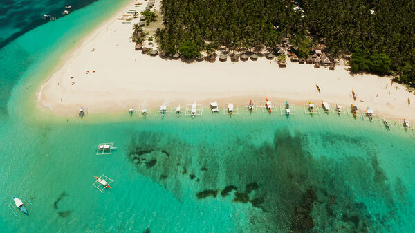 Tropical Daco Island with a sandy beach and tourists.