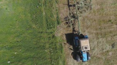 Tarlada tırmıkla tırmık taşıyan traktör..