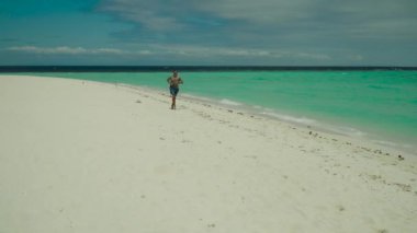 Adam kumlu bir plaj boyunca joggin.