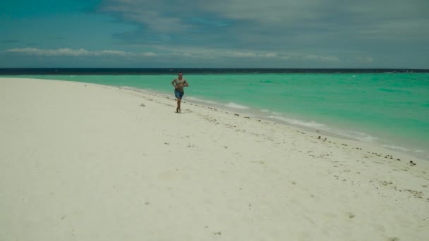 Hombre trotar a lo largo de una playa de arena . — Vídeo de stock