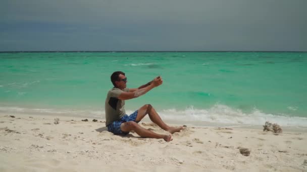 Man met een tablet op een tropisch strand. — Stockvideo