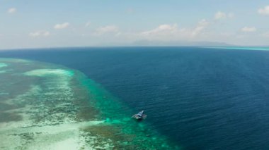 Mavi sularda bir mercan resifinde tekne. Balabac, Palawan, Filipinler.