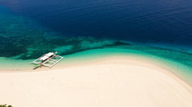 Beyaz kumdan oluşan tropik plaj, üst manzara. Sahilde bir turist teknesi. Sakin plaj sahnesi.