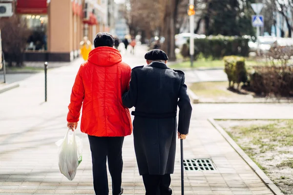 Rückansicht eines älteren Ehepaares, das auf der Straße spaziert. — Stockfoto