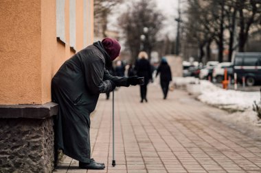 Photo of old hungry homeless female beggar beg for alms and on street. clipart