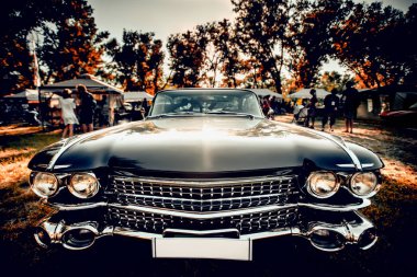 Close-up wide-angled photo of black vintage retro car with shining chrome radiator grille, bumper and headlamps clipart