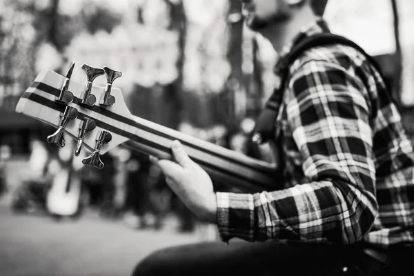 Черно-белое фото музыканта, играющего на шестиструнной бас-гитаре на улице перед людьми . — стоковое фото