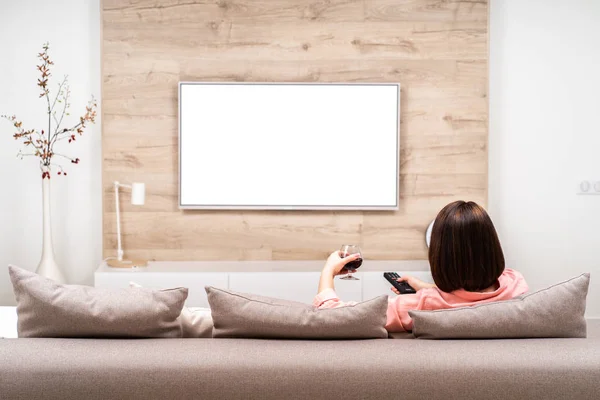 Kanepe kırmızı şarap ile rahatlatıcı ve tv izlerken güzel mutlu kahverengi saçlı genç erkek. Boş ekran