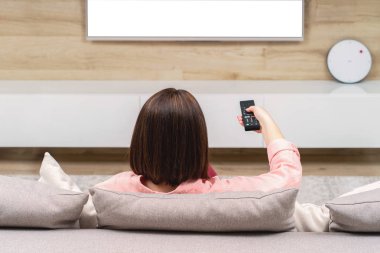 Arkadan kanal değiştirme Tv izlerken kanepenin üstüne oturan yalnız hüzünlü depresif genç kadın, görünüşü. Boş ekran