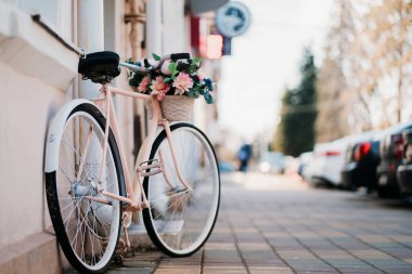 Şehirde sokakta kapının yanında duran çiçek sepeti ile beyaz Bisiklet.