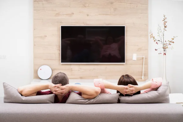 Arkadan görünüş çift erkek ve kadın evinde istirahat, birlikte kanepede oturan ve Tv izlerken
