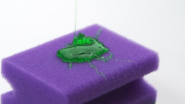 Super macro close up footage of purple sponge for dish and pouring detergent in form of green gel. — Stock Video