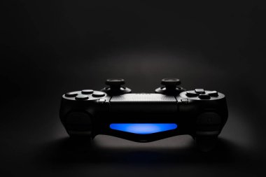 Siyah arkaplanda oyun konsolu joystick denetleyicisinin yakın plan fotoğrafı mavi ışık ile.