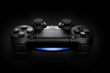 Siyah arkaplanda oyun konsolu joystick denetleyicisinin yakın plan fotoğrafı mavi ışık ile.