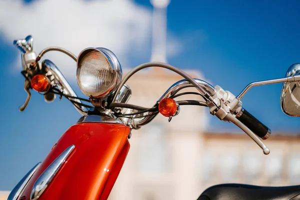 Detalle cromado de primer plano y faro de scooter vintage retro naranja bajo el cielo azul y el sol frente a la torre desenfocada — Foto de Stock