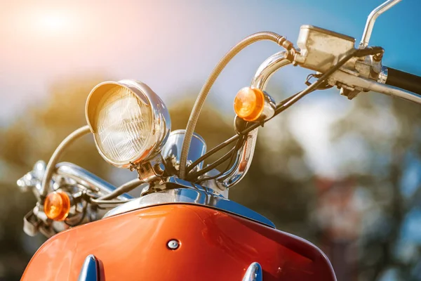 Detalle de primer plano cromado y faro de scooter vintage retro naranja bajo el cielo azul y el sol sobre el fondo borroso . — Foto de Stock