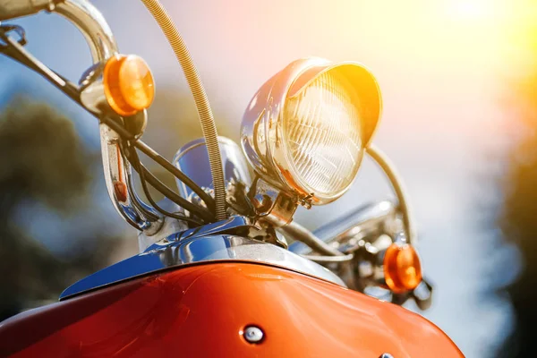 Närbild krom detalj och strålkastare av orange retro vintage skoter under blå himmel och sol på suddig bakgrund. — Stockfoto