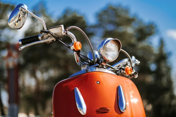 Detalle de primer plano cromado y faro de scooter vintage retro naranja bajo el cielo azul y el sol sobre el fondo borroso . — Foto de Stock