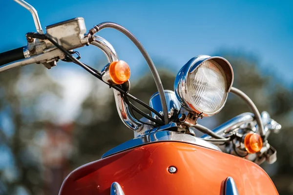 Closeup detalhe cromado e farol de scooter vintage retro laranja sob o céu azul e sol sobre o fundo borrado . — Fotografia de Stock