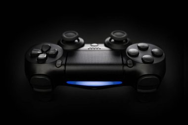 Siyah arkaplanda oyun konsolu joystick denetleyicisinin yakın plan fotoğrafı mavi ışık ile.