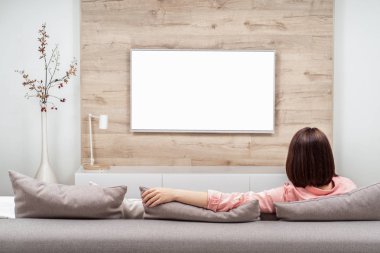 Arkadan görünüşü güzel genç kadın lüks appartments dinlenme, kanepede oturan ve Tv izlerken.