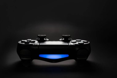 Siyah arkaplanda oyun konsolu joystick denetleyicisinin yakın plan fotoğrafı mavi ışık ile.