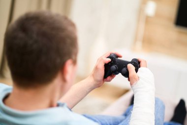 Alçı da kırık kolu olan adam kırmızı kan oyunu ile ve Tv önünde denetleyici tutan. Oyun bağımlılığı kavramı.